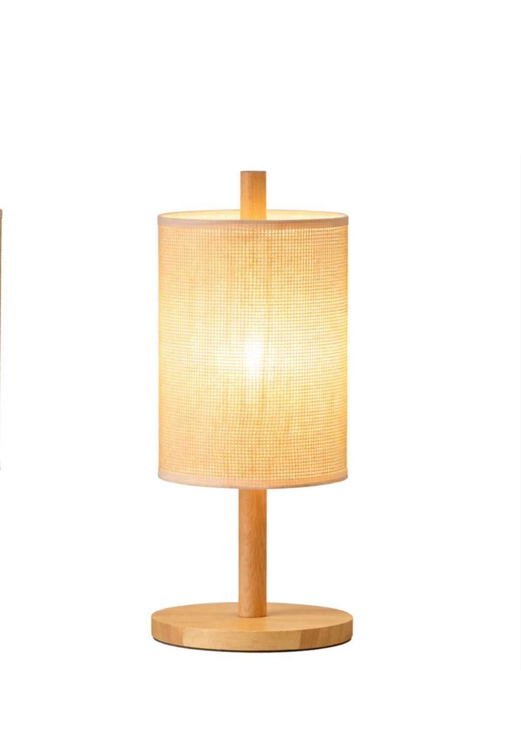 The Aria table lamp lit on a side table in a living room