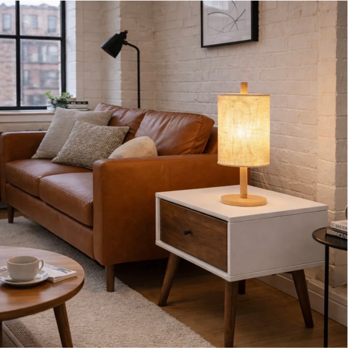 The Aria table lamp unlit on a side table next to a leather sofa