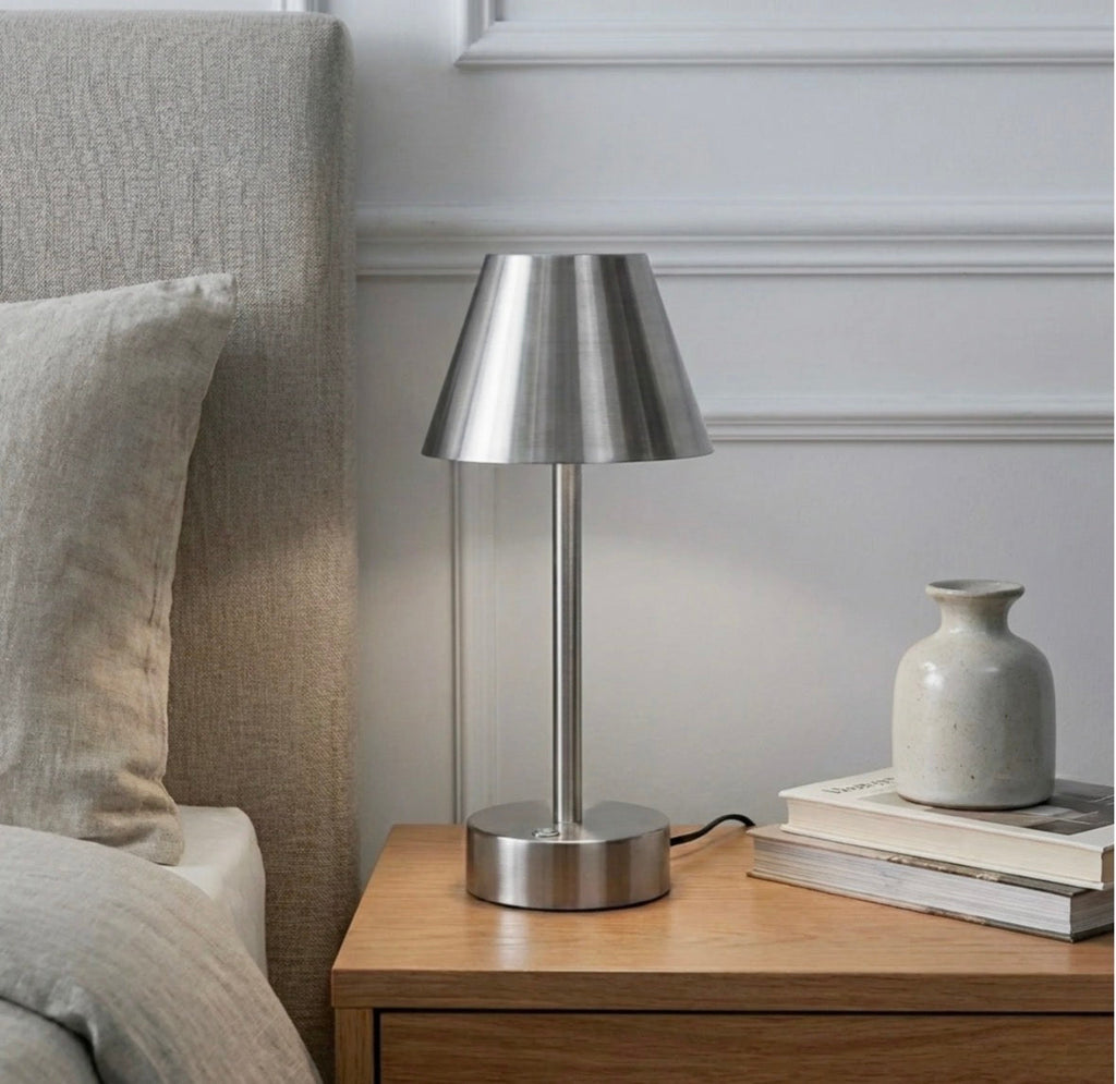 The Lumière brushed nickel cordless LED table lamp unlit on a wooden nightstand